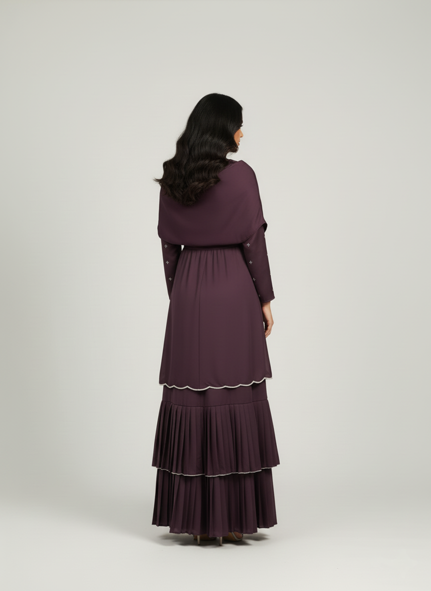 Woman wearing a long, dark purple dress with a hood on a white background