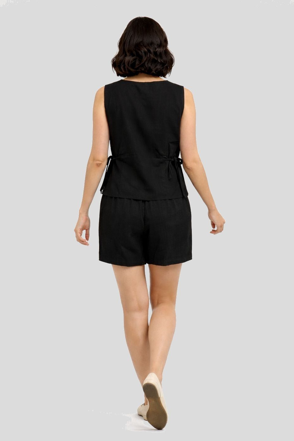 Woman wearing a black sleeveless top and shorts set on a light gray background