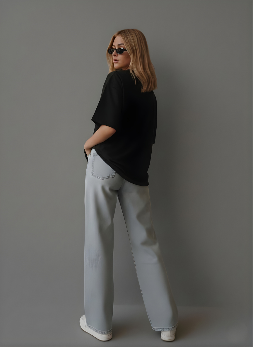 Person wearing a black oversized shirt and light gray pants against a gray background