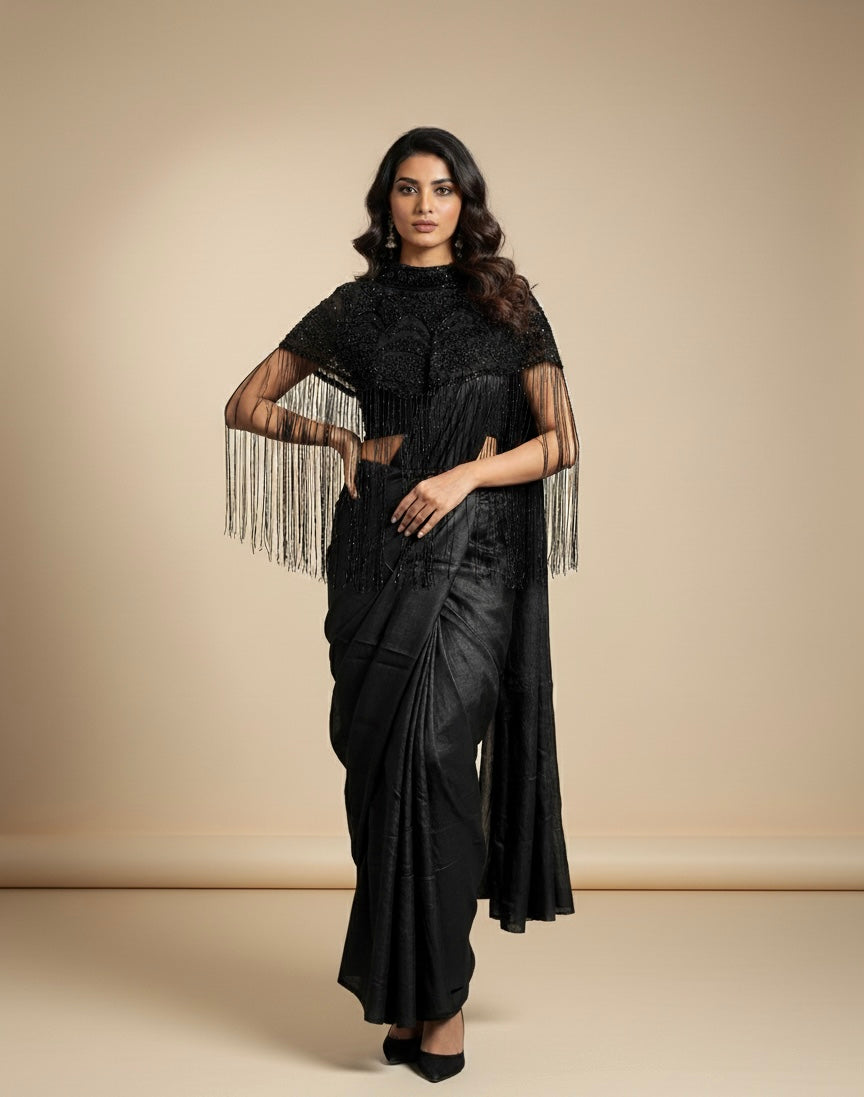 Woman wearing a black saree with a matching blouse against a beige background