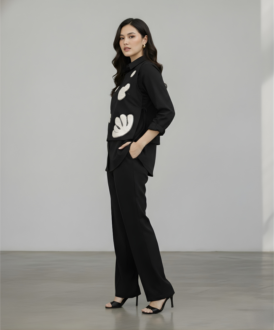 Woman wearing a black outfit with white floral patterns against a plain background