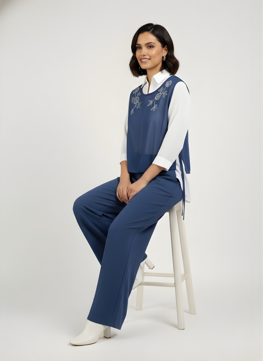 Woman sitting on a stool wearing a blue and white outfit against a white background