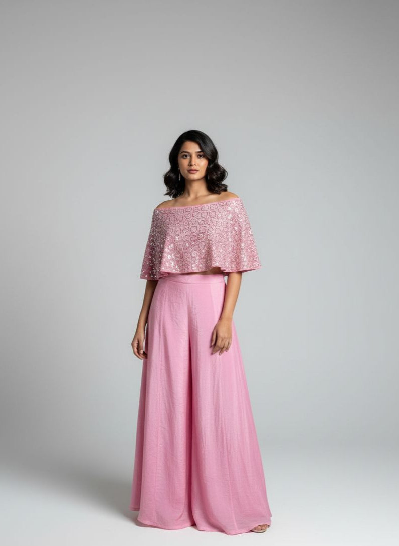 Woman wearing a pink off-shoulder top and pink pants on a gray background