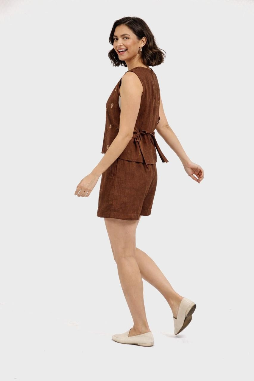 Woman wearing a brown sleeveless top and shorts set on a white background