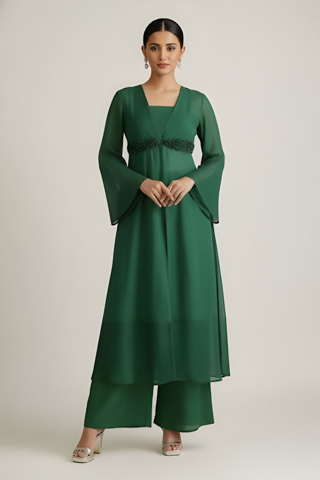Woman wearing a green dress with bell sleeves against a plain background