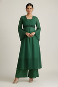 Woman wearing a green dress with bell sleeves against a plain background