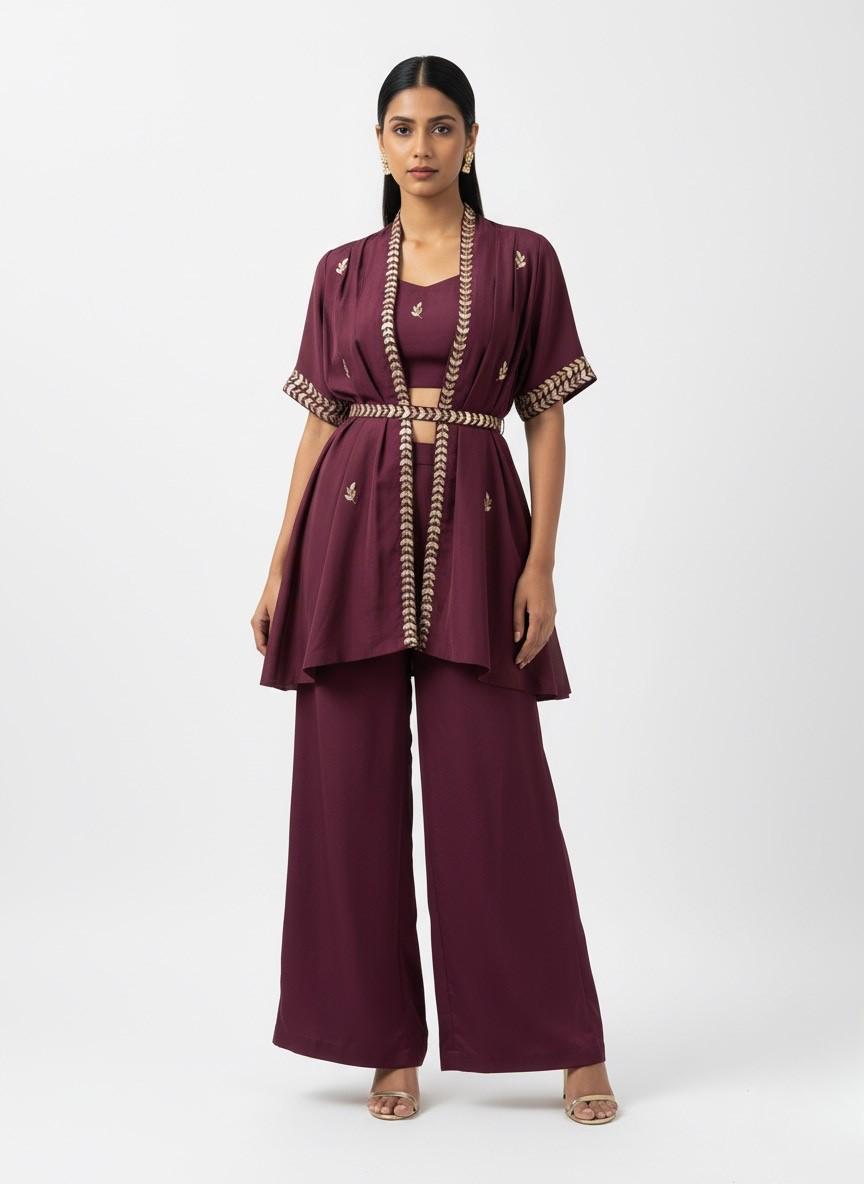 Woman wearing a burgundy outfit with gold accents on a white background