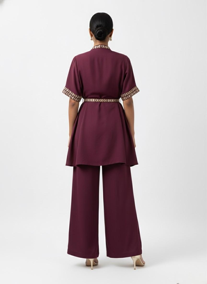 Person wearing a maroonoutfit with a belt on a white background