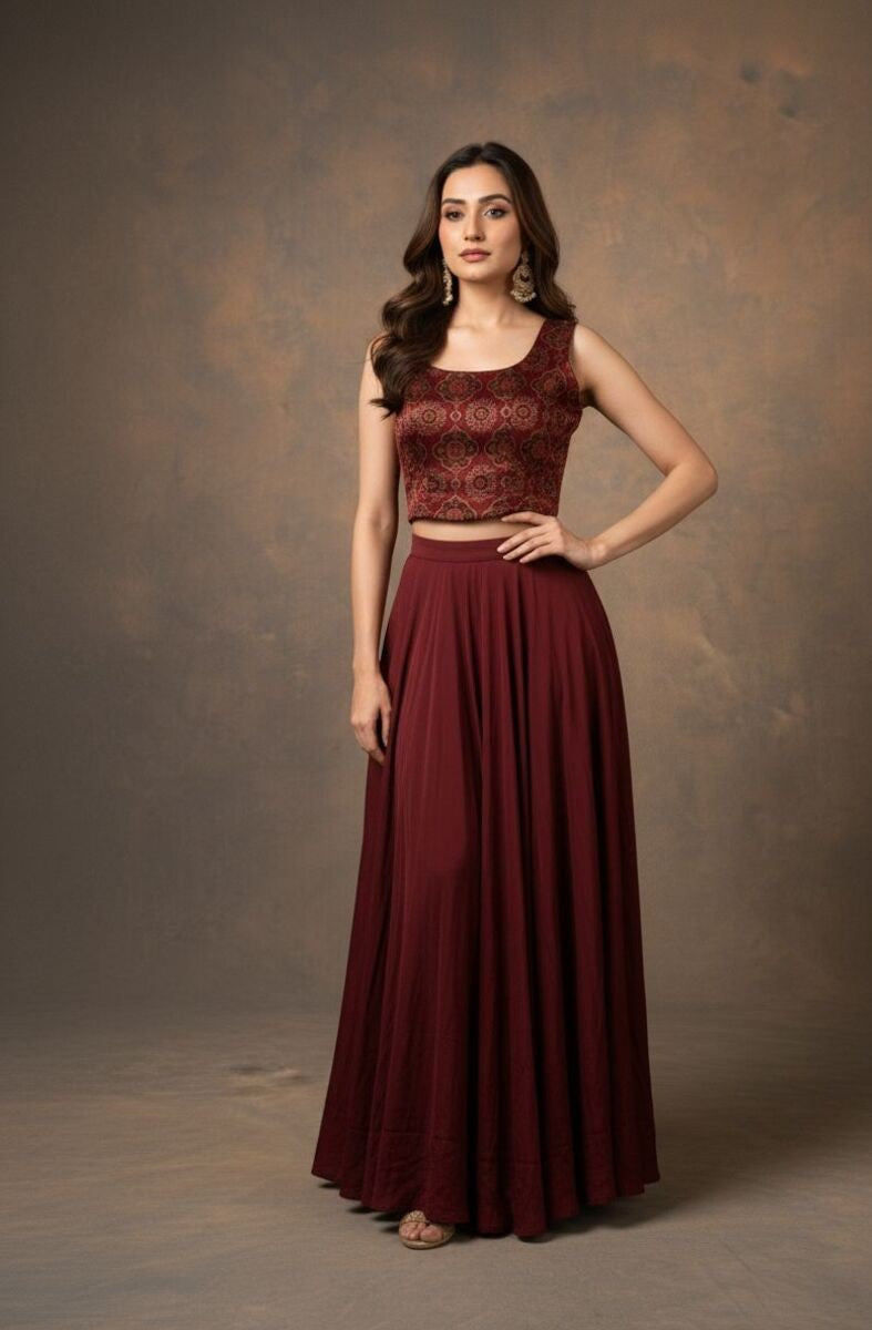 Woman wearing a maroon traditional outfit with a patterned top and flowing skirt against a brown background
