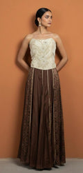 Woman wearing a strapless white lace top and brown patterned skirt against an orange background