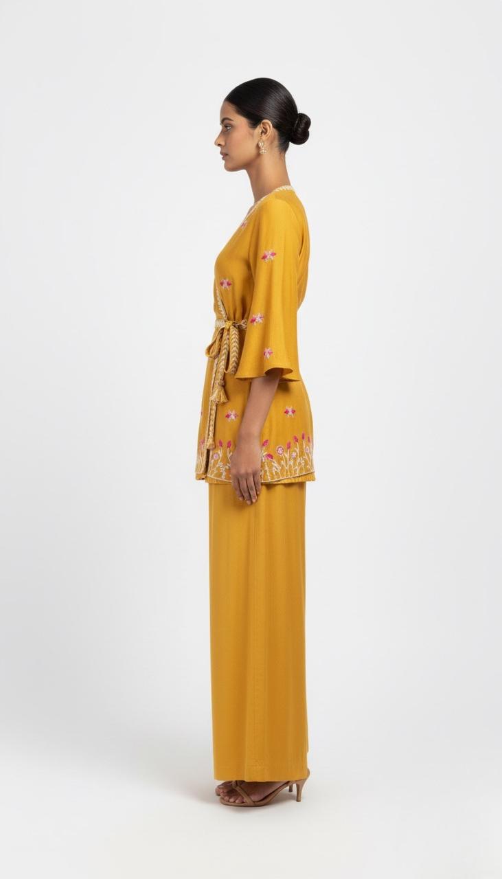 Woman wearing a mustard yellow outfit with floral patterns on a white background