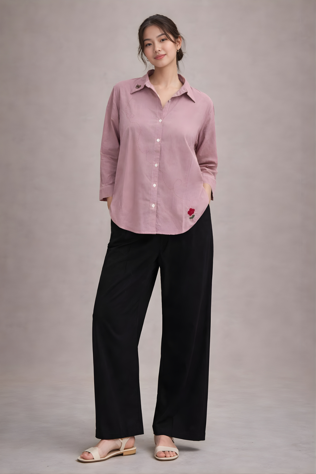 Woman wearing a pink shirt and black pants on a gray background