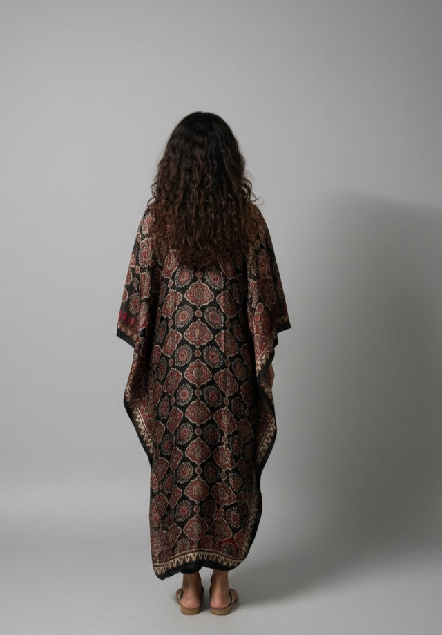 Person wearing a patterned long garment against a plain background