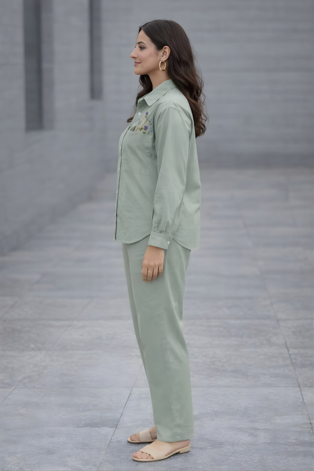 Woman wearing a light green outfit standing on a gray pavement.