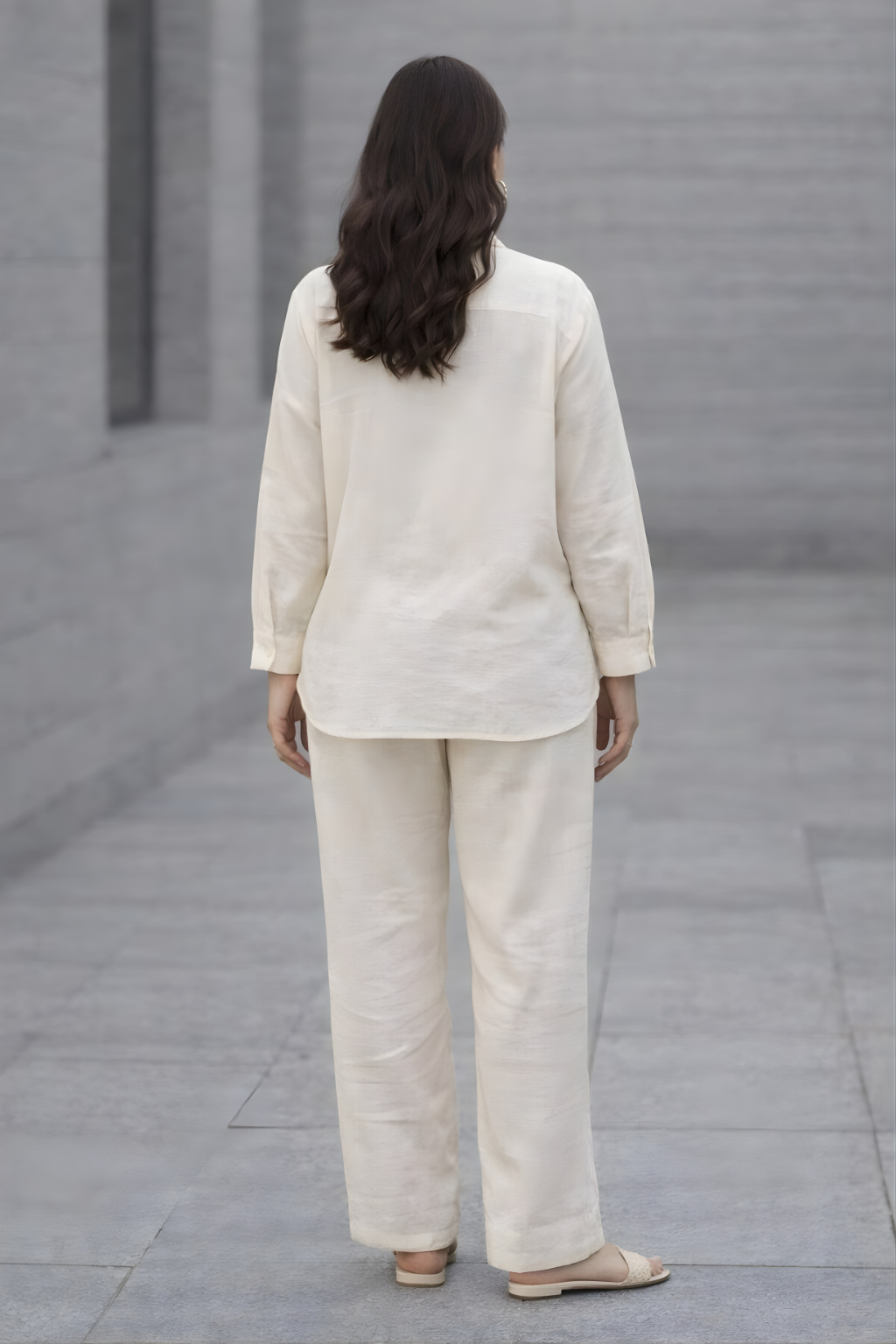 Person wearing a beige suit standing on a gray pavement.