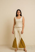 Woman wearing a beige top and patterned pants on a beige background