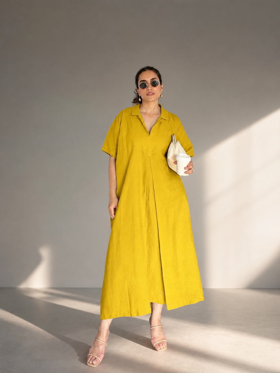 Woman wearing mustard yellow linen maxi dress in studio sunlight 