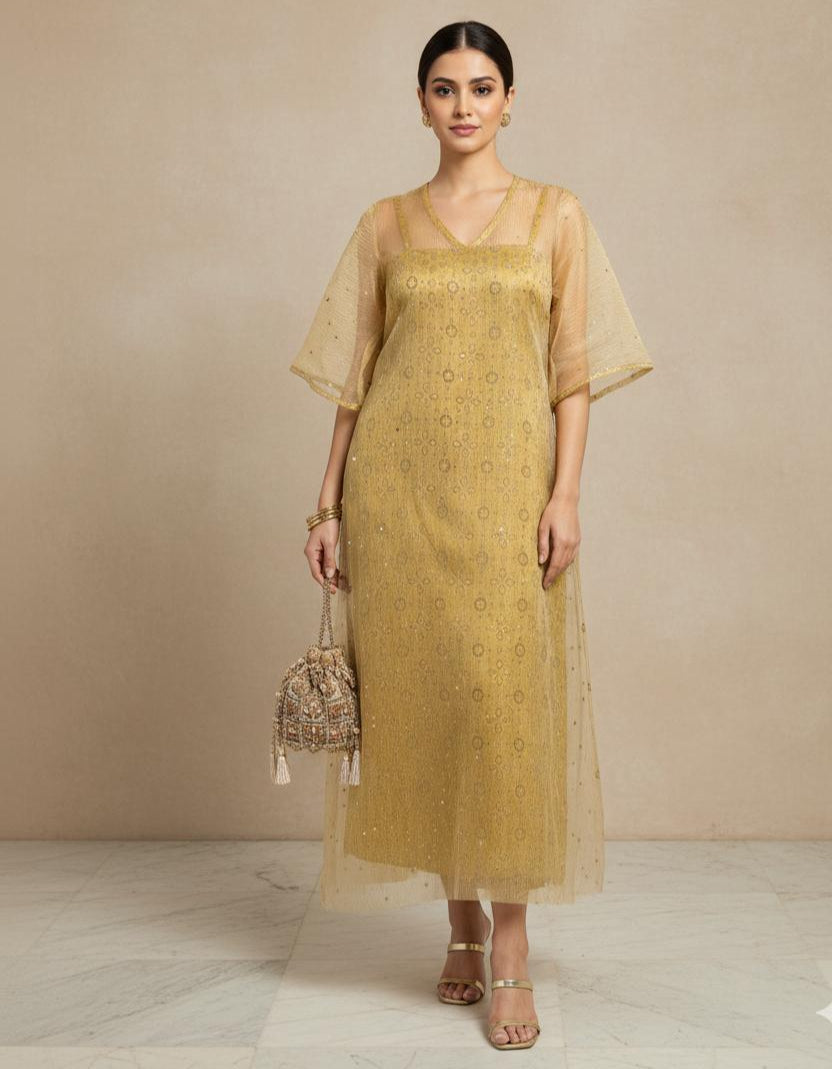 Woman wearing a mustard yellow dress with sheer sleeves against a beige background
