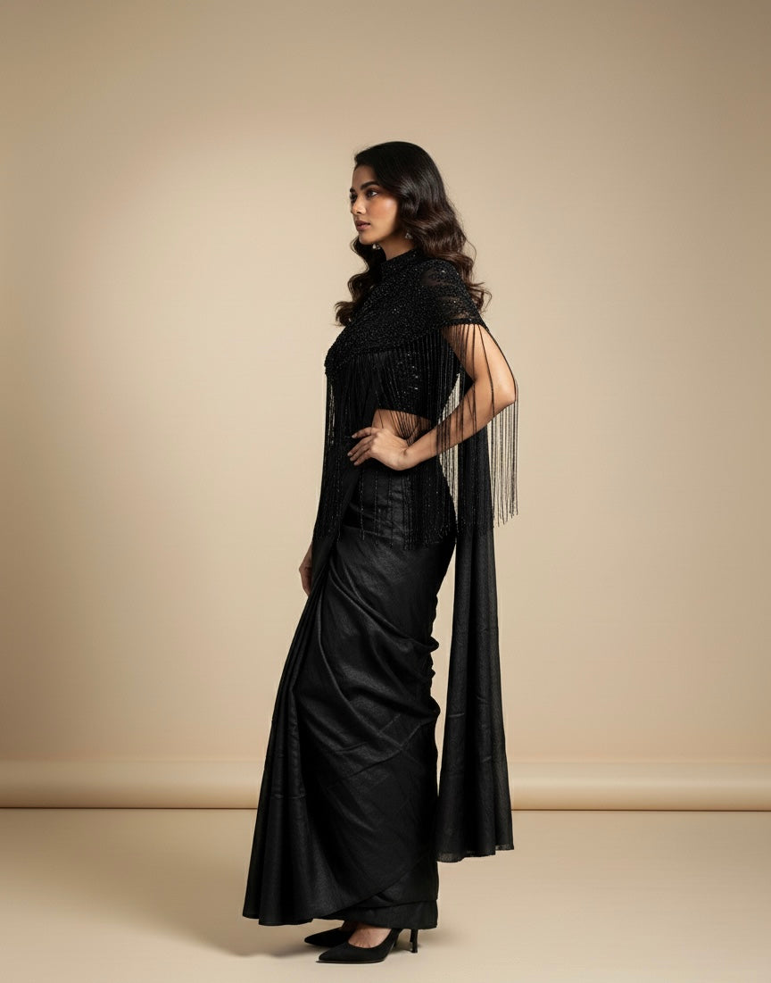 Woman wearing a black outfit with a long, flowing design against a beige background