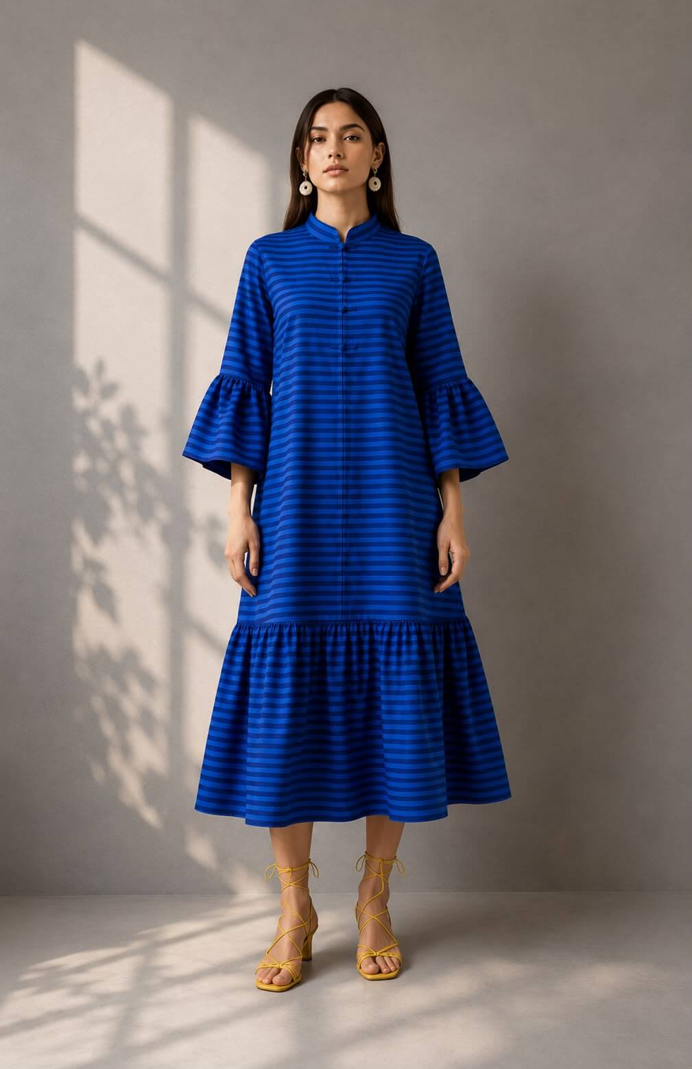 Woman wearing a cobalt blue striped cotton midi dress with bell sleeves and a mandarin collar.