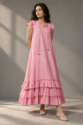  Woman wearing a blush pink tiered midi dress with floral embellishments and ruffled sleeves
