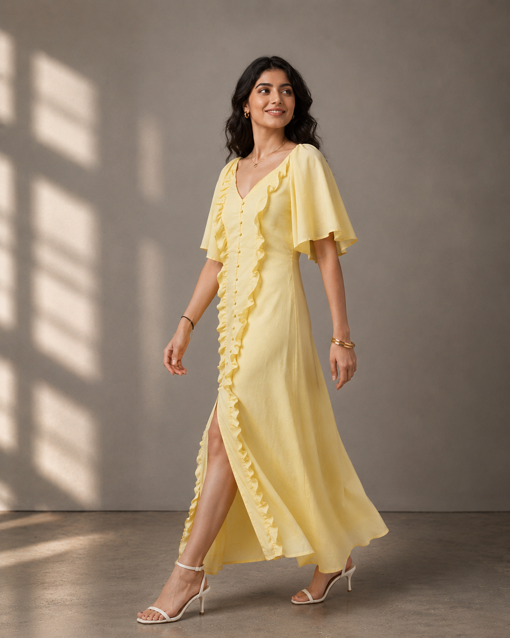 Side walking pose of a woman wearing a butter yellow ruffle maxi dress with flutter sleeves.