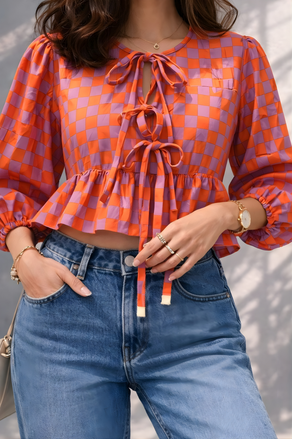 Close-up of bow tie details on orange checkered peplum blouse