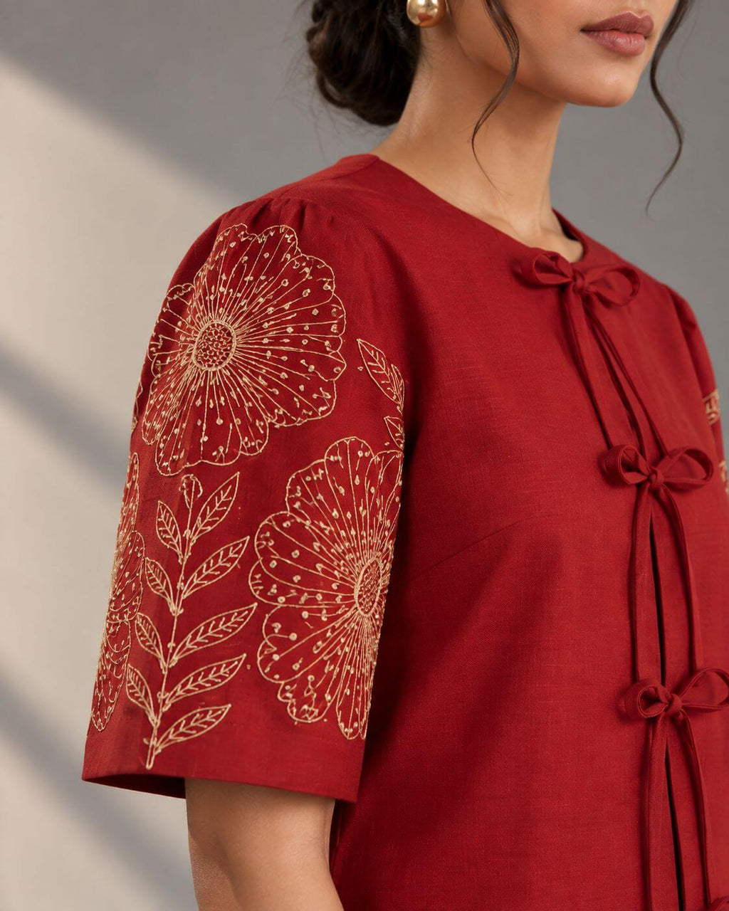Close-up of intricate Zardosi floral embroidery on crimson crape silk sleeves