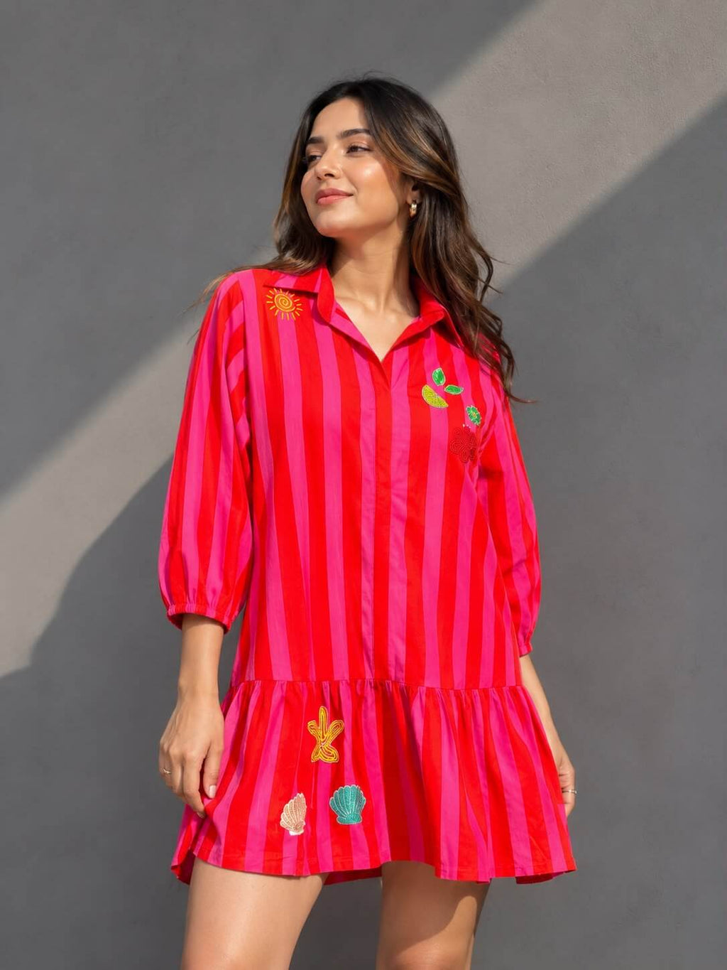 Women's embellished pink striped cotton shirt dress with handcrafted motifs and ruffle hem.
