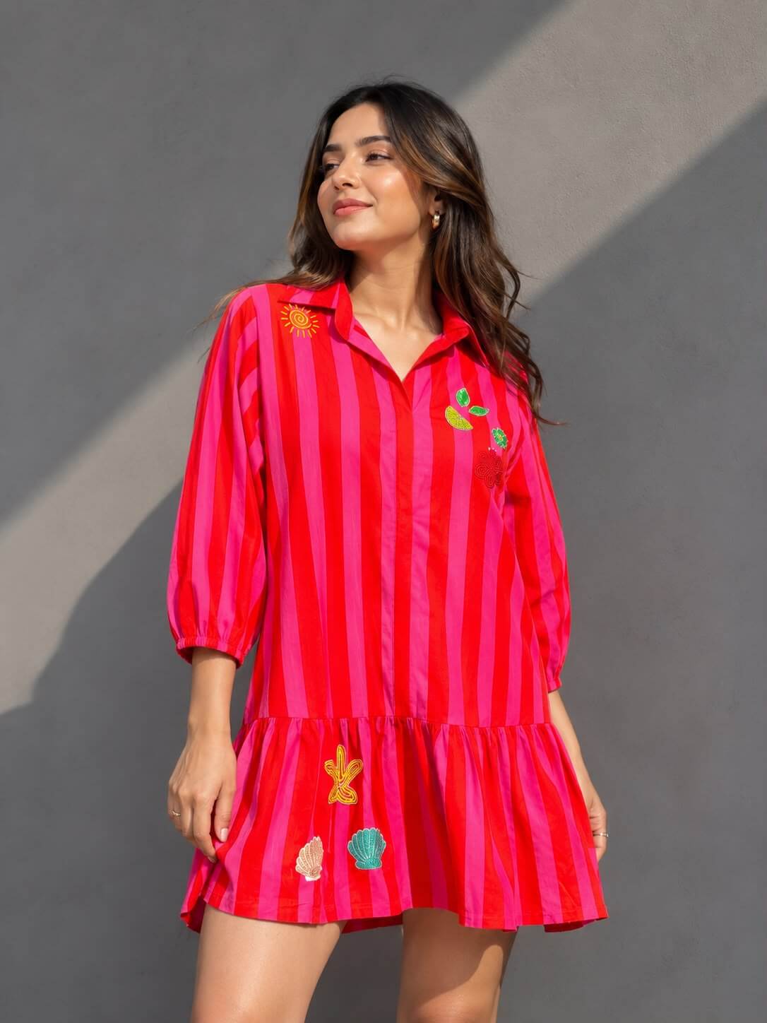 Women's embellished pink striped cotton shirt dress with handcrafted motifs and ruffle hem.