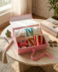 Gehru Joy Box featuring a customized alphabet T-shirt, handcrafted Rakhi, red and white striped ceramic mug, cinnamon fragrance bar, Choco Pie, and premium pink gift box.