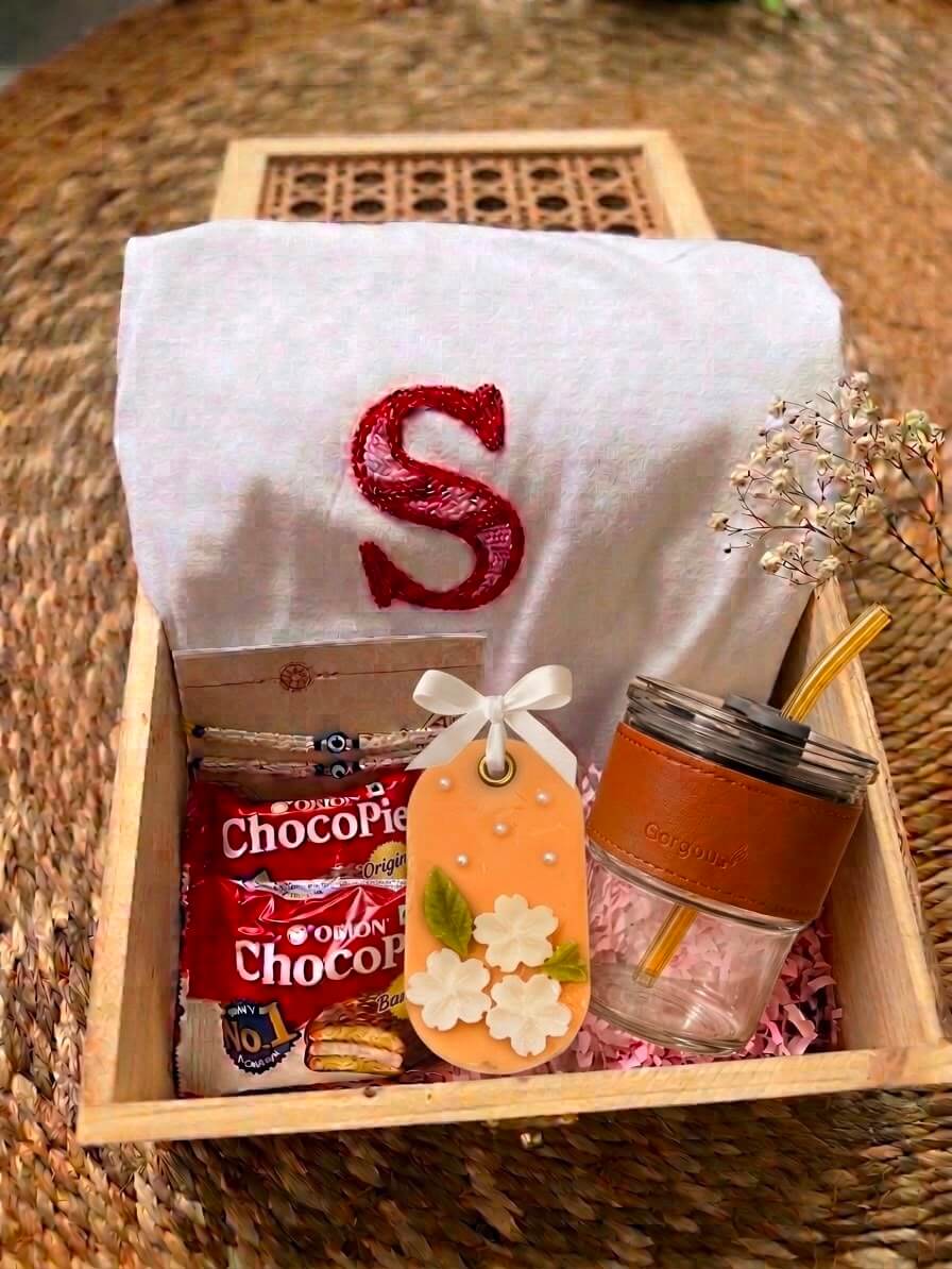 Wooden Raksha Bandhan gift box with personalised initial t-shirt, rakhi, Choco Pie, handcrafted floral sandal bar and glass tumbler with straw.