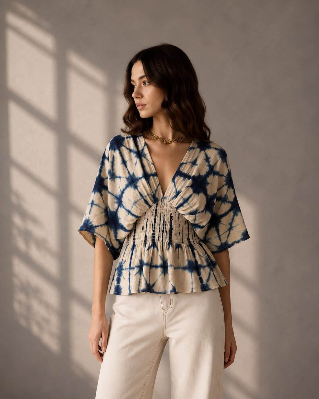 Woman wearing an indigo shibori print peplum top with smocked waist detailing.