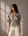Woman wearing an indigo shibori print peplum top with smocked waist detailing.