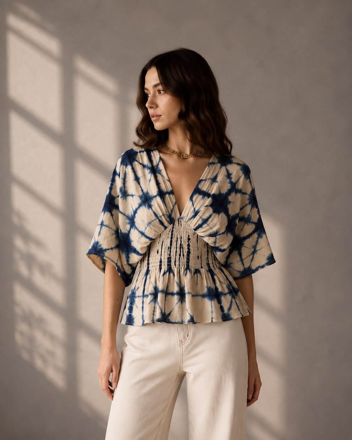 Woman wearing an indigo shibori print peplum top with smocked waist detailing.