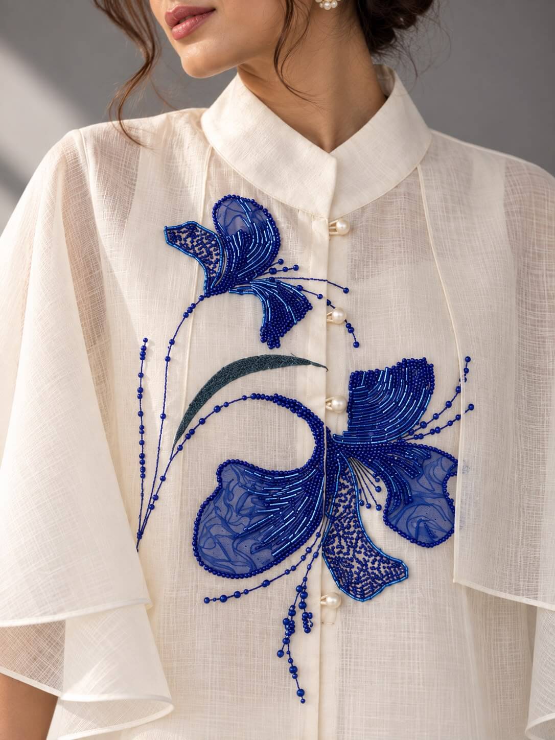Close-up of intricate blue tubelight embellishment work on ivory cotton top