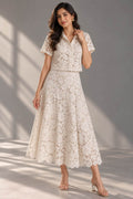 Woman wearing an ivory floral lace co-ord set with a short-sleeve collared shirt and flared midi skirt.