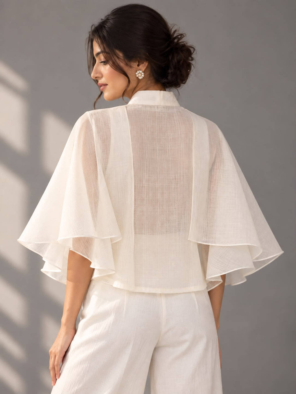 Ivory designer cotton top featuring statement layered ruffle sleeves and blue floral embellishment