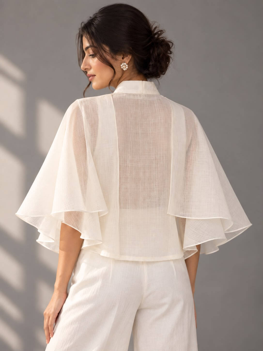 Ivory designer cotton top featuring statement layered ruffle sleeves and blue floral embellishment
