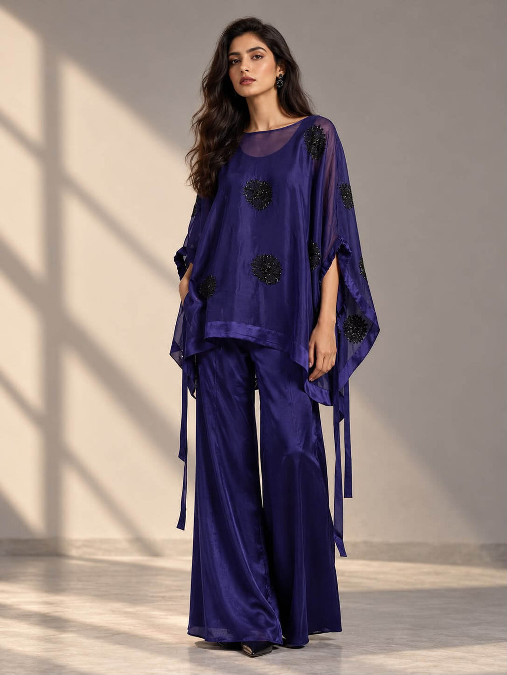 Woman wearing a navy organza co-ord set with black tubelight embellishments and wide-leg trousers by Gehru Label.
