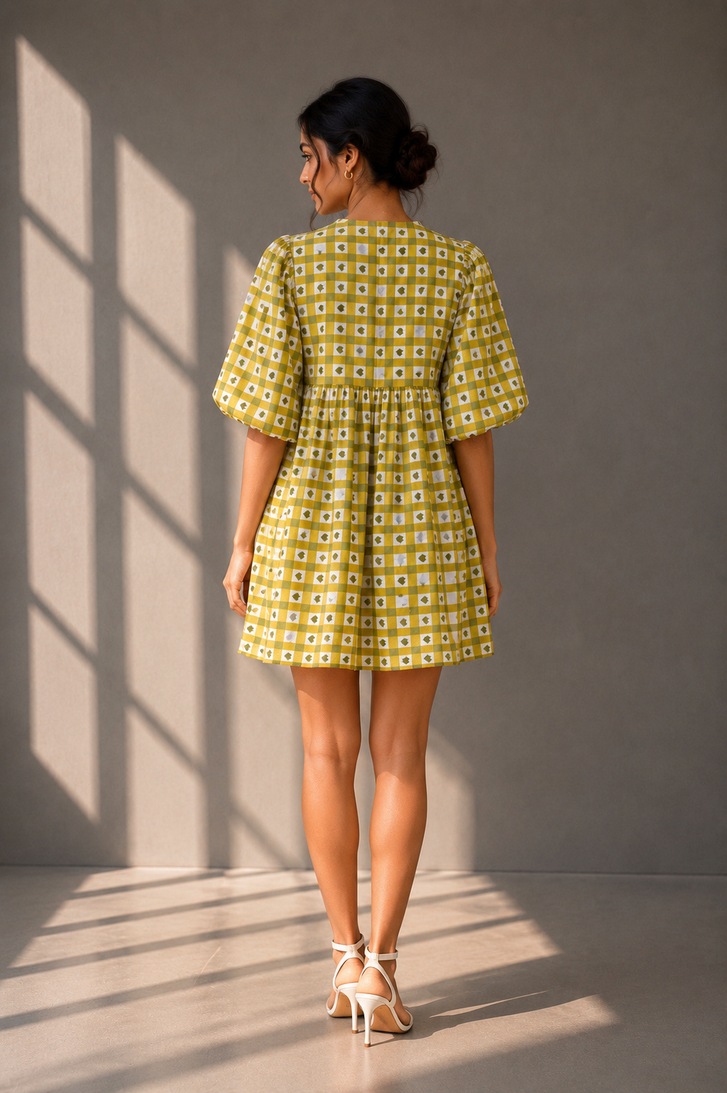 Back view of olive heart check mini babydoll dress with puff sleeves on grey studio background