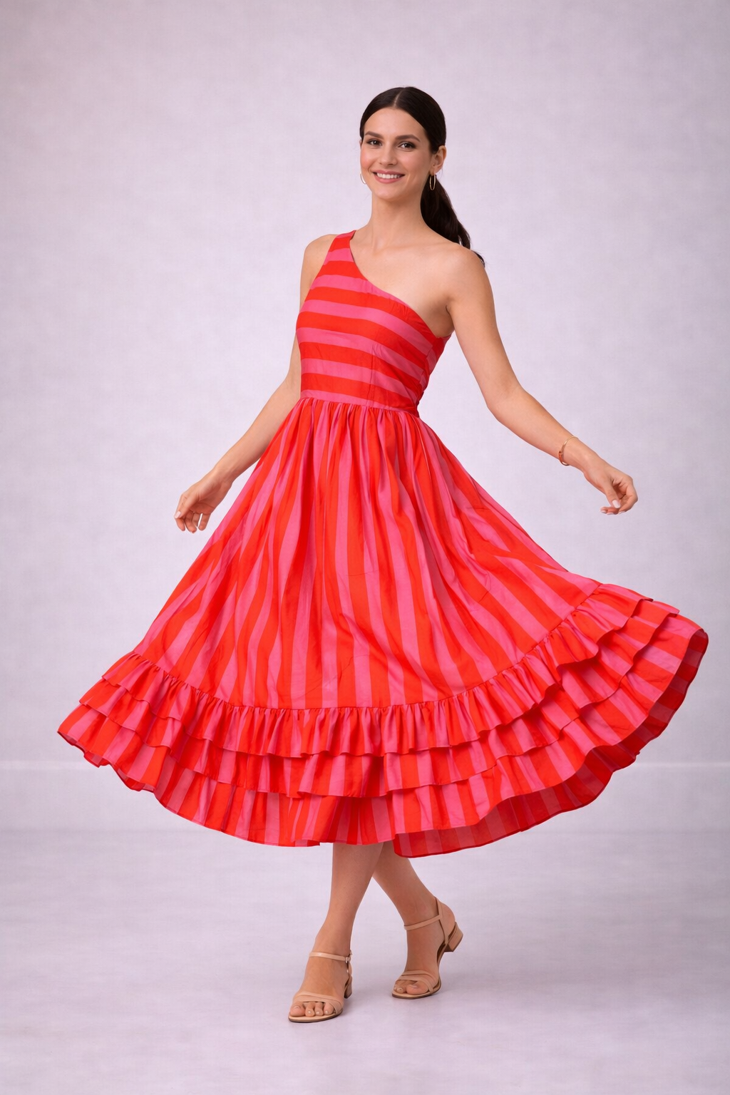 Woman wearing a pink and orange striped dress with ruffled layers on a plain background