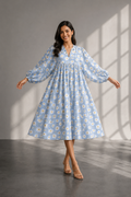 Woman wearing a powder blue floral cotton maxi dress with daisy print in studio sunlight background.