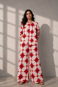 Woman wearing a handcrafted red and ivory tie-dye cotton co-ord set with a button-down shirt and wide-leg trousers.