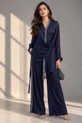 Woman wearing a navy georgette co-ord outfit with a draped asymmetrical top, silver gotta lace and matching wide-leg trousers against a grey studio background.
